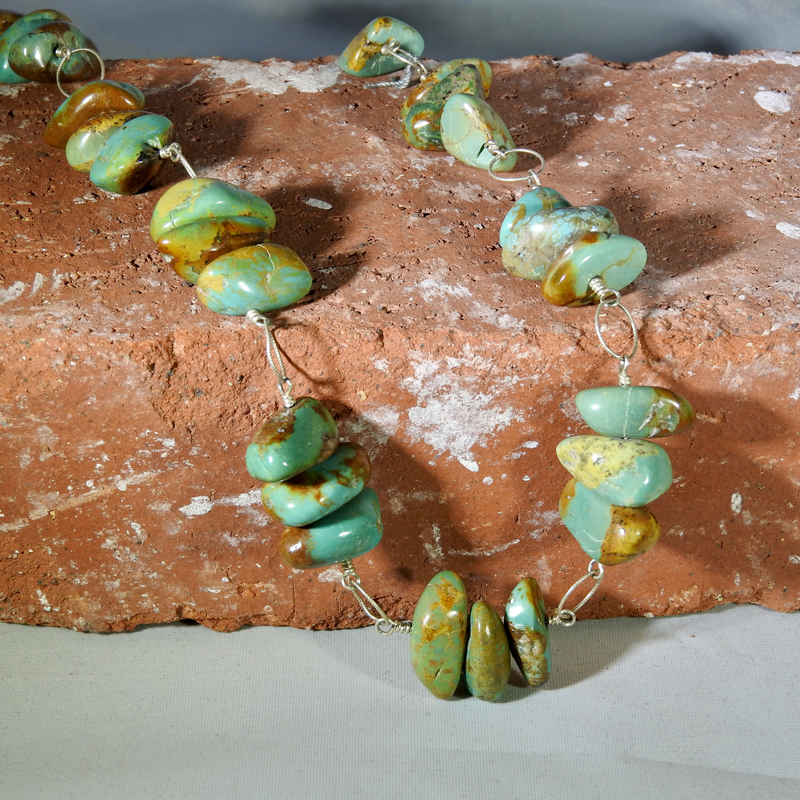 Turquoise beaded pottery necklace laying on a red brick